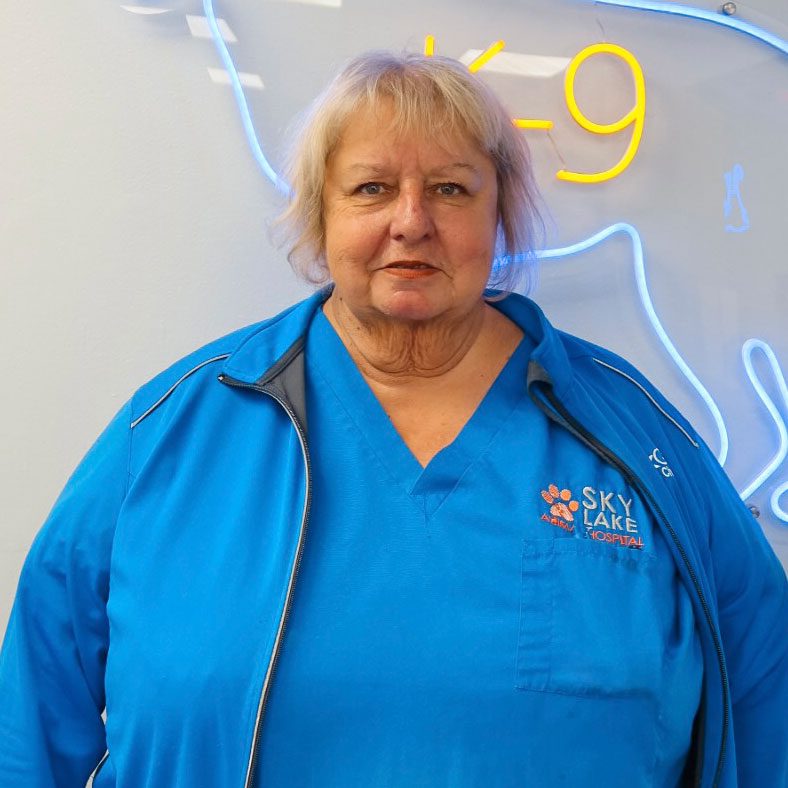 smiling female veterinary technician standing in front of neon dog wall decoration