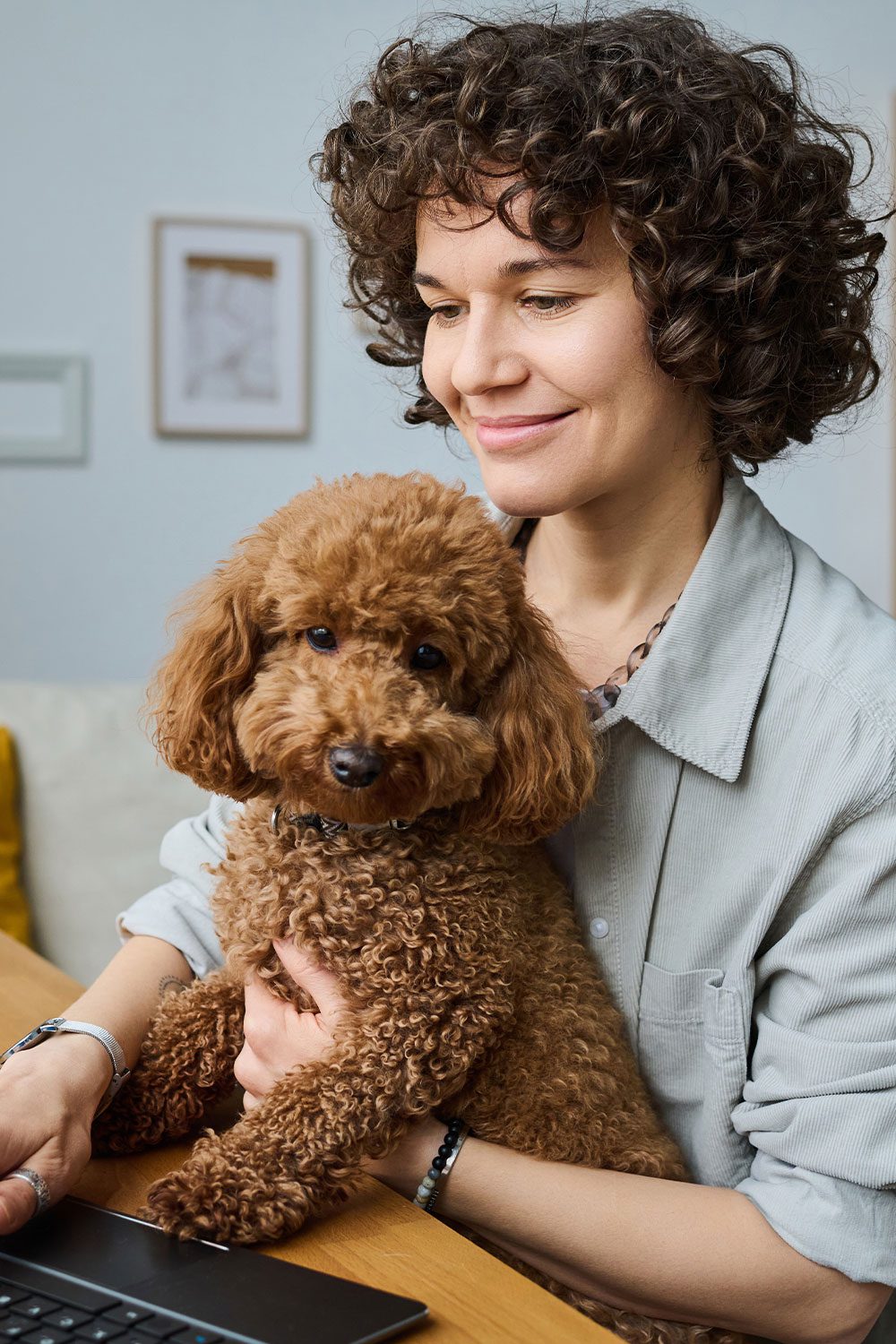 woman holding brown curly haired dog
