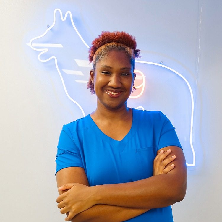Female with short auburn hair wearing a blue V-neck tshirt crossing her arms